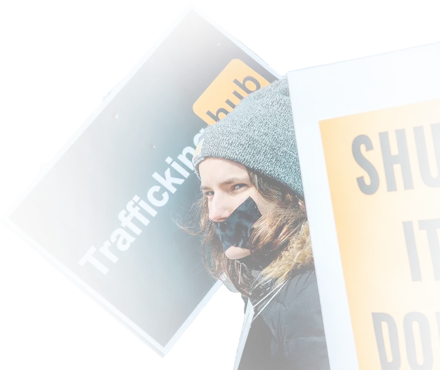 A woman with black tape on her mouth holds up a Traffickinghub sign at a protest